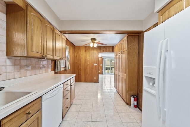 kitchen featuring white appliances, ceiling fan, sink, light tile patterned floors, and wood walls