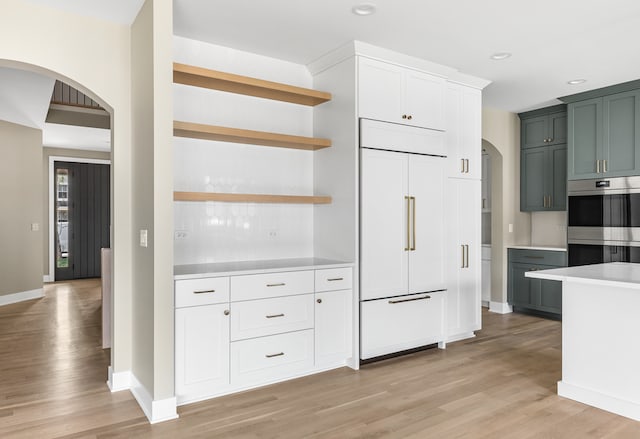 kitchen featuring green cabinetry, paneled fridge, light hardwood / wood-style floors, white cabinets, and double oven