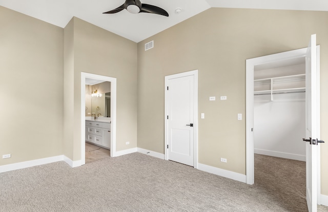 unfurnished bedroom featuring a closet, light carpet, high vaulted ceiling, ceiling fan, and ensuite bathroom