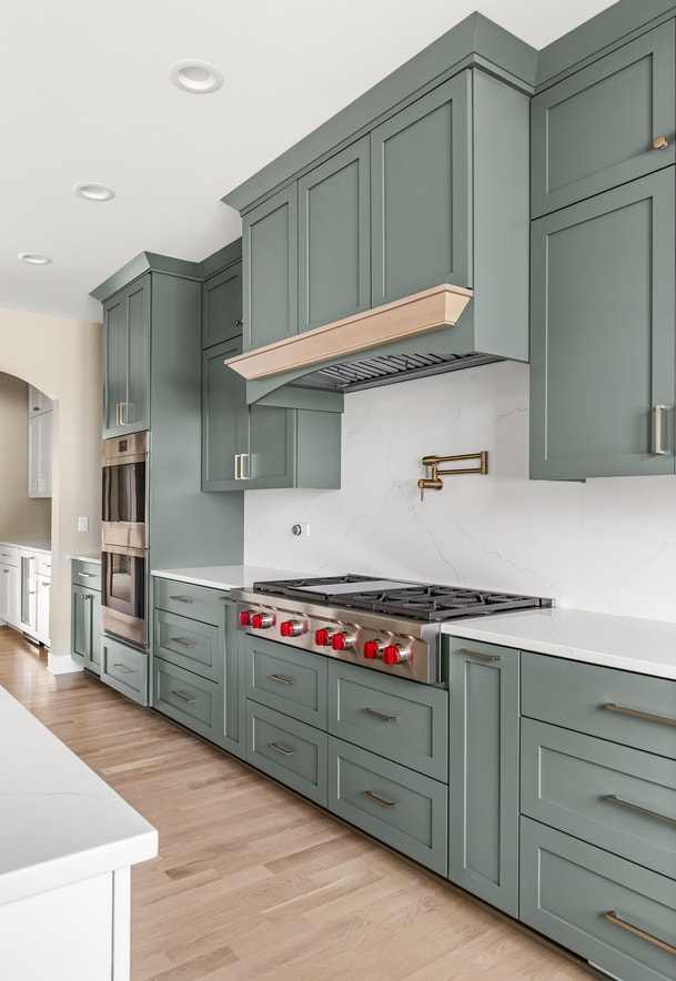 kitchen with appliances with stainless steel finishes, green cabinetry, light hardwood / wood-style flooring, and backsplash