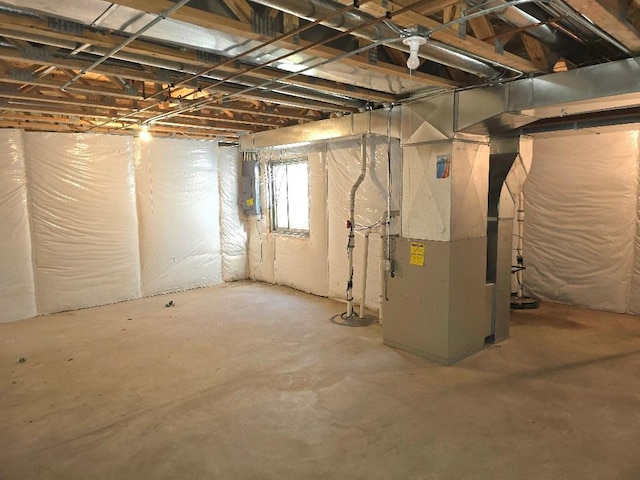 basement featuring electric panel and heating unit