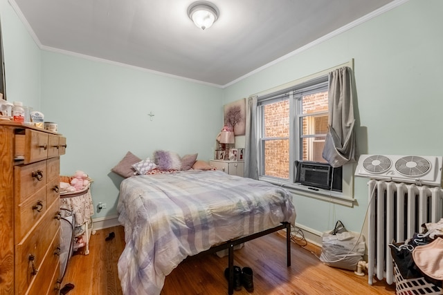 bedroom featuring radiator, wood-type flooring, cooling unit, and crown molding