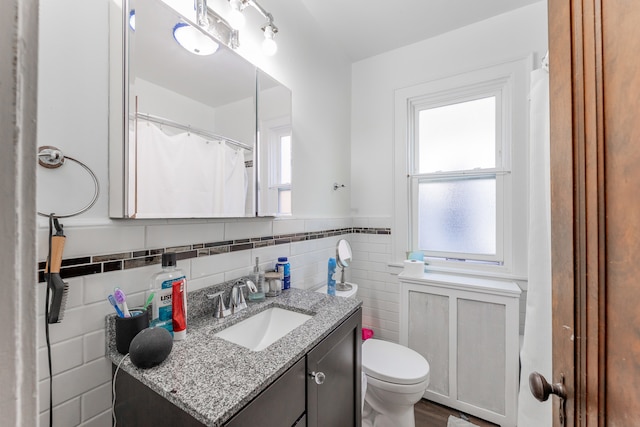 bathroom featuring tile walls, vanity, and toilet