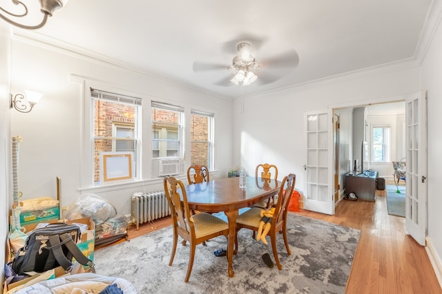 dining room featuring radiator heating unit, cooling unit, ornamental molding, ceiling fan, and light wood-type flooring