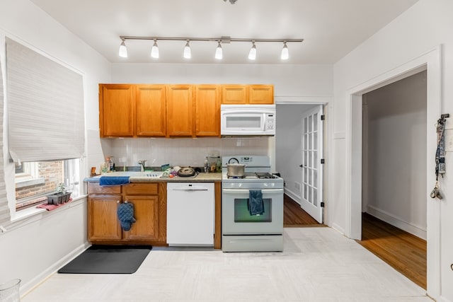 kitchen featuring light wood-type flooring, tasteful backsplash, sink, and white appliances