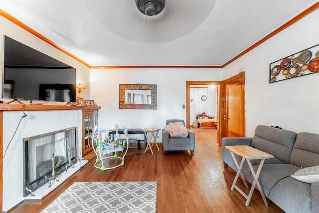 living room featuring ceiling fan, wood-type flooring, ornamental molding, and a fireplace