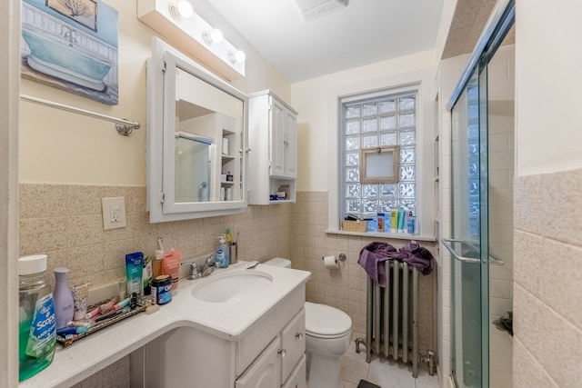 bathroom with tile walls, vanity, toilet, and radiator