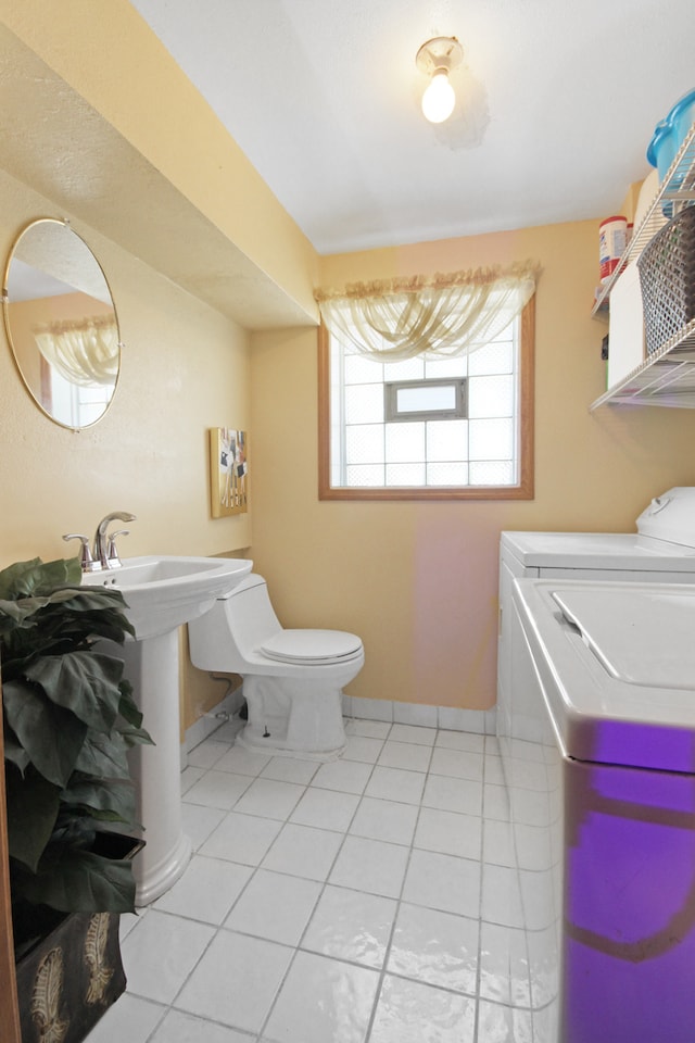 bathroom featuring washer and dryer, tile patterned flooring, and toilet