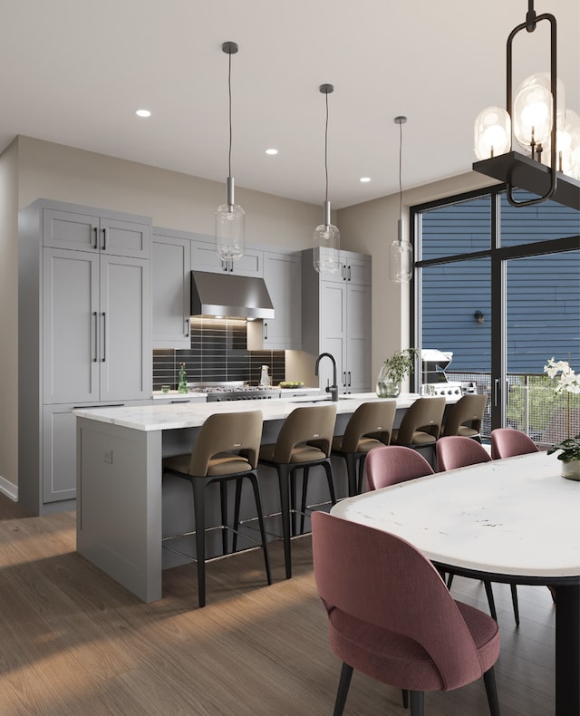 kitchen with pendant lighting, backsplash, dark hardwood / wood-style flooring, and an island with sink