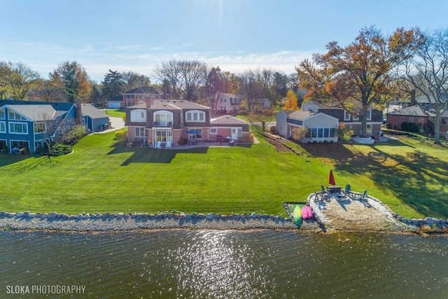 back of house with a water view, a yard, and a patio