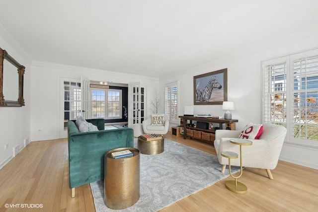 living room featuring plenty of natural light, wood-type flooring, crown molding, and french doors