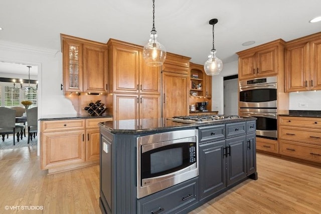 kitchen featuring pendant lighting, appliances with stainless steel finishes, a center island, dark stone counters, and gray cabinetry