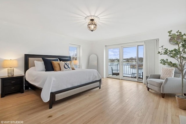 bedroom with access to outside, a water view, and light hardwood / wood-style flooring