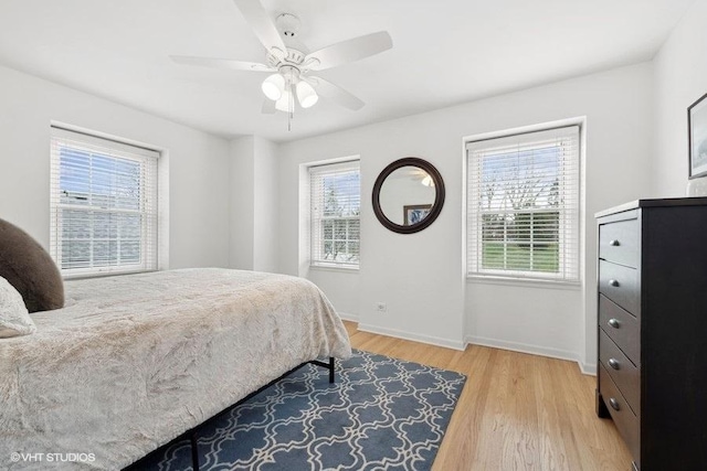 bedroom with ceiling fan, multiple windows, and light hardwood / wood-style flooring