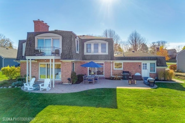 rear view of house with a lawn, a balcony, and a patio