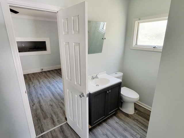bathroom featuring wood finished floors, toilet, vanity, and baseboards