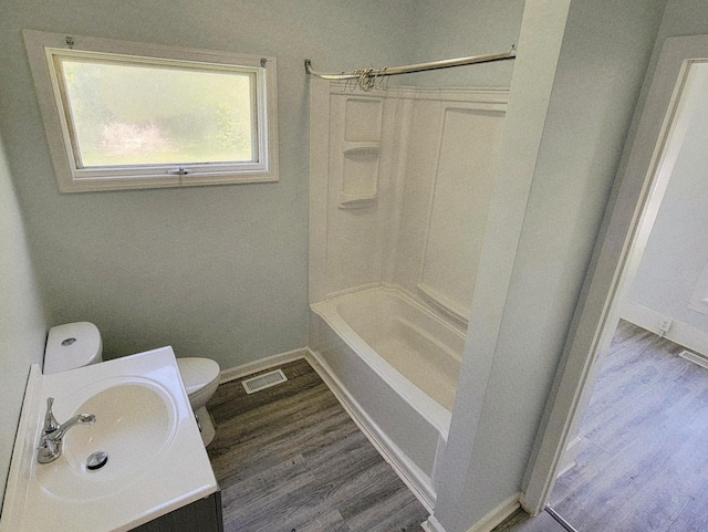 full bath featuring toilet, wood finished floors, vanity, baseboards, and shower / bath combination