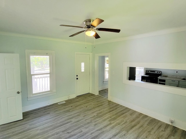 foyer with ornamental molding, wood finished floors, ceiling fan, and baseboards