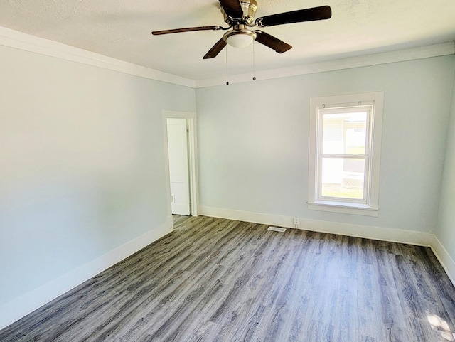 unfurnished room featuring wood finished floors, baseboards, crown molding, and a ceiling fan