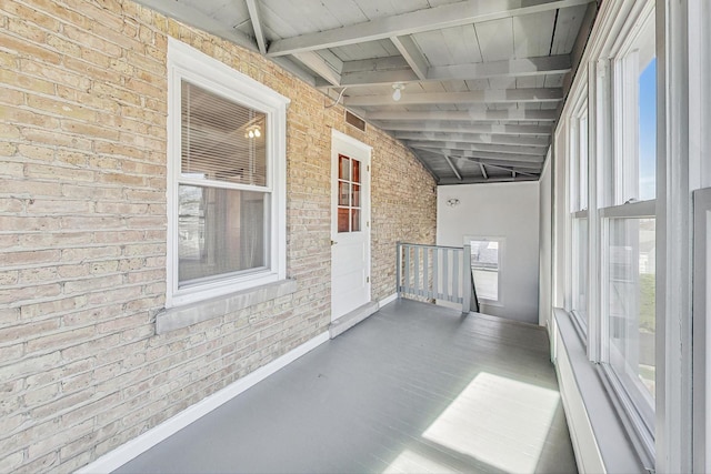 unfurnished sunroom featuring lofted ceiling with beams