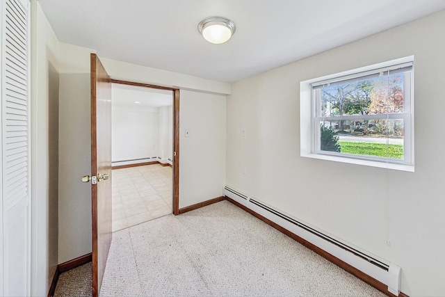 carpeted spare room featuring a baseboard heating unit