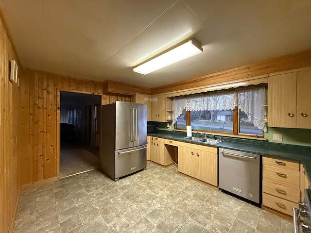 kitchen with light brown cabinets, sink, stainless steel appliances, and wood walls