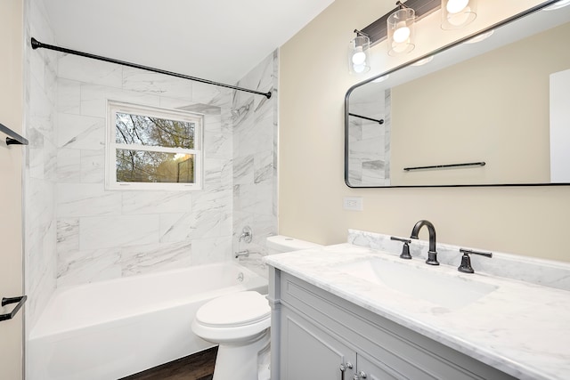 full bathroom featuring hardwood / wood-style flooring, vanity, tiled shower / bath combo, and toilet