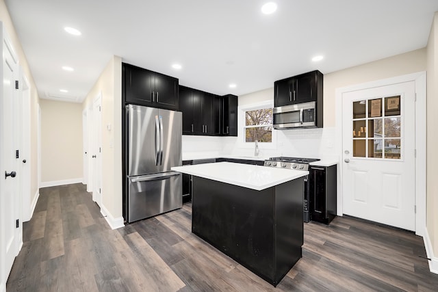 kitchen with stainless steel appliances, backsplash, dark hardwood / wood-style flooring, sink, and a center island