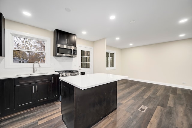 kitchen with stainless steel appliances, dark hardwood / wood-style flooring, sink, and a kitchen island