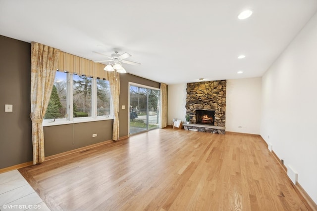 unfurnished living room with ceiling fan, light hardwood / wood-style floors, and a stone fireplace