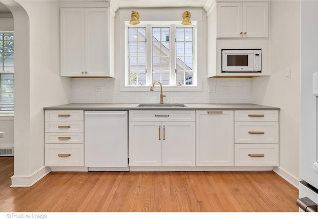 kitchen with white appliances, sink, backsplash, and light hardwood / wood-style floors