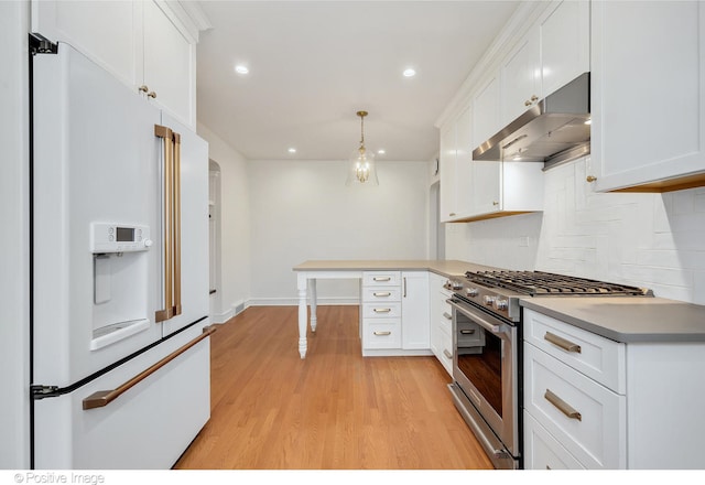 kitchen with premium appliances, extractor fan, decorative light fixtures, and white cabinets