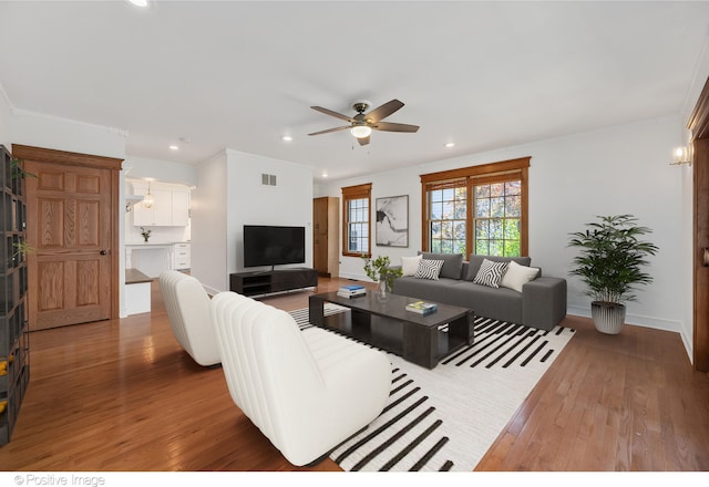 living room featuring crown molding, hardwood / wood-style flooring, and ceiling fan