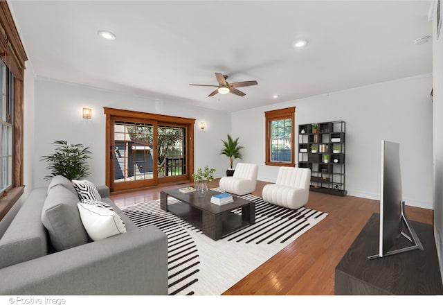 living room featuring ceiling fan, a wealth of natural light, dark hardwood / wood-style floors, and ornamental molding