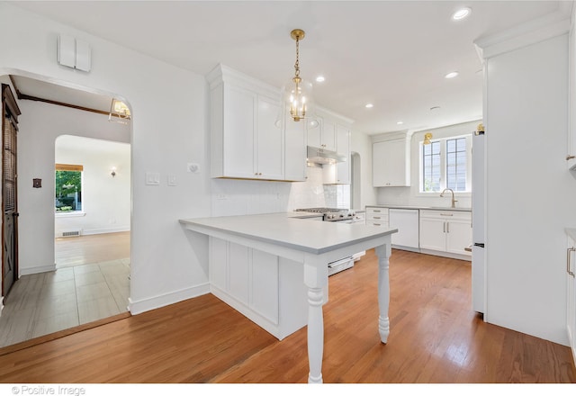 kitchen with light hardwood / wood-style floors, white cabinetry, a breakfast bar, and kitchen peninsula