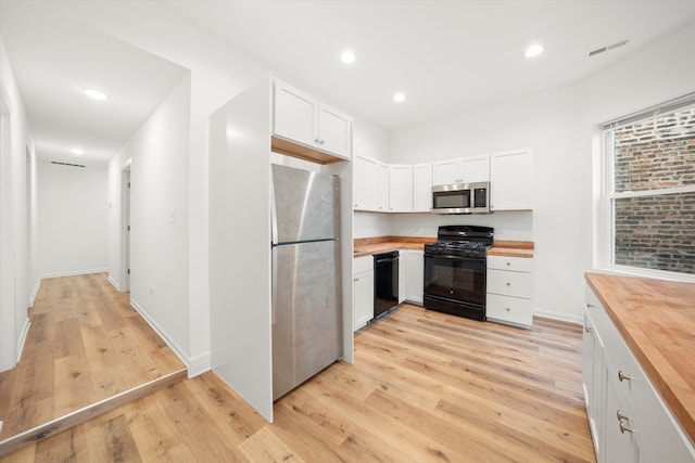 kitchen featuring wooden counters, white cabinets, and black appliances