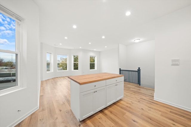 kitchen featuring butcher block countertops, white cabinetry, and light hardwood / wood-style flooring