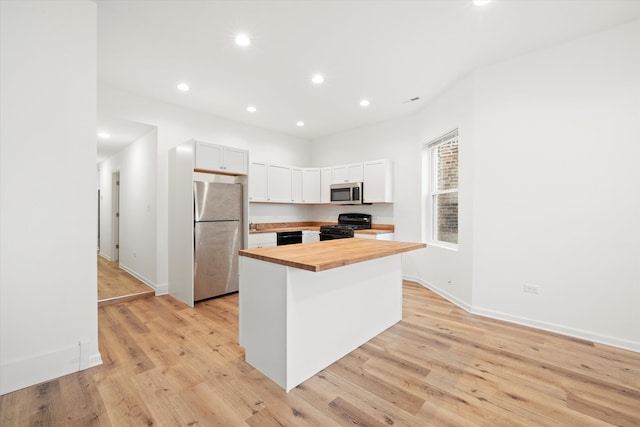 kitchen featuring butcher block counters, a center island, black appliances, and light hardwood / wood-style floors