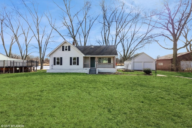 rear view of house featuring a yard, a detached garage, a chimney, and an outbuilding