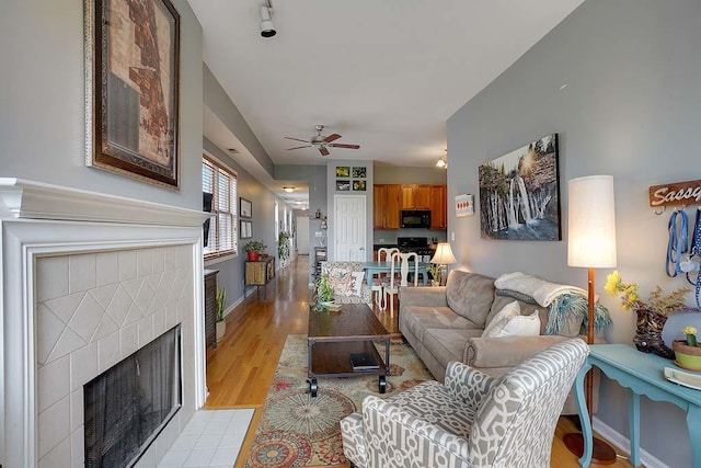 living room with ceiling fan, a fireplace, and light hardwood / wood-style floors