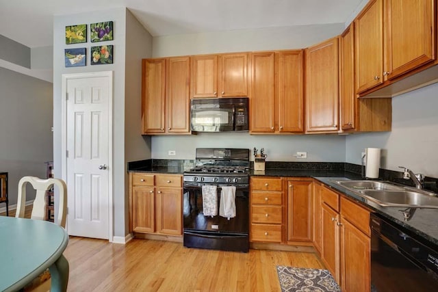 kitchen featuring dark stone counters, sink, light hardwood / wood-style flooring, and black appliances