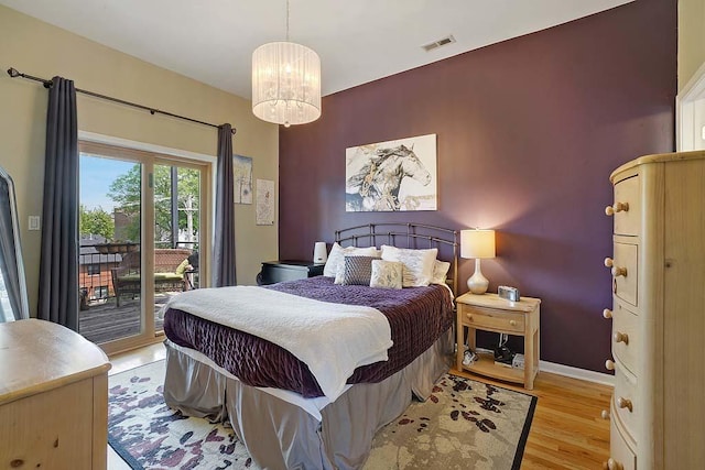 bedroom featuring access to exterior, a chandelier, and light hardwood / wood-style floors