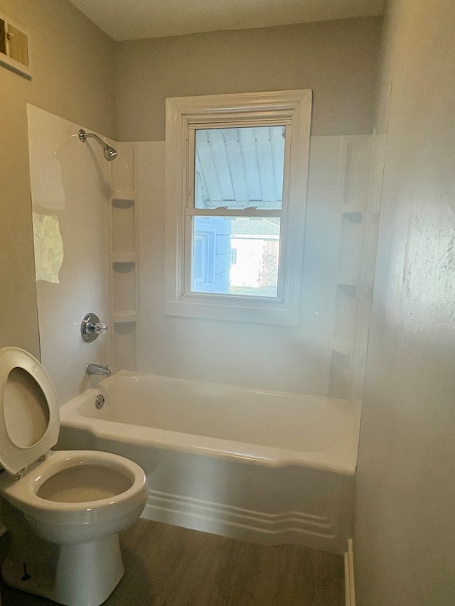 bathroom featuring hardwood / wood-style floors, washtub / shower combination, and toilet