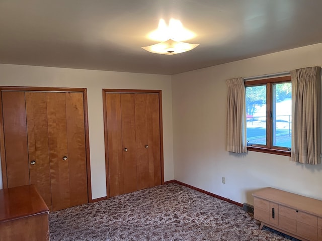 unfurnished bedroom featuring multiple closets and carpet floors