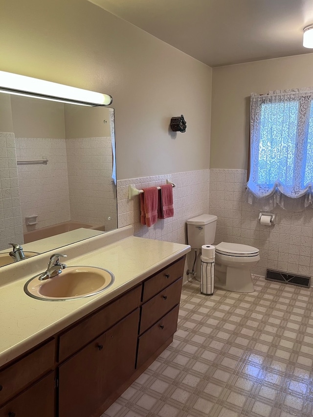 bathroom with tile walls, vanity, and toilet