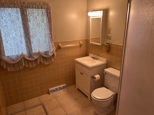 bathroom with toilet, vanity, tile walls, and tile patterned flooring