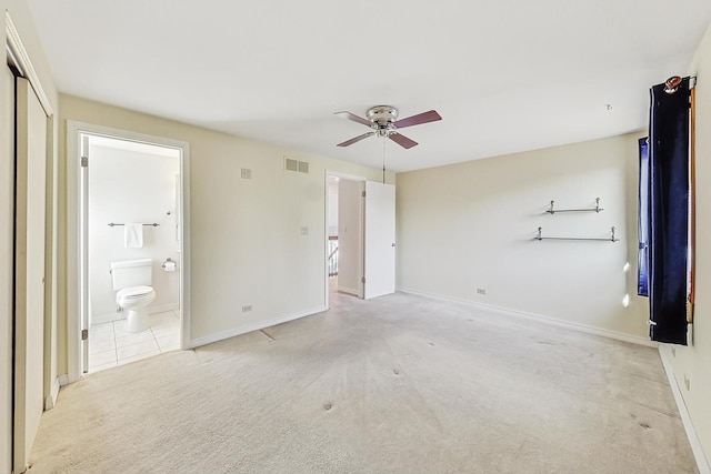 unfurnished bedroom featuring light carpet, connected bathroom, and ceiling fan