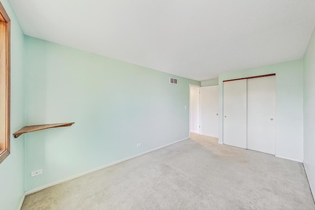 unfurnished bedroom featuring a closet and light carpet