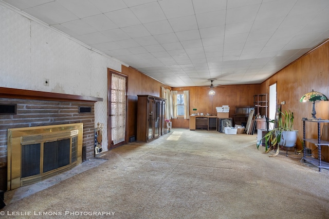 unfurnished living room featuring wood walls, carpet floors, and a brick fireplace