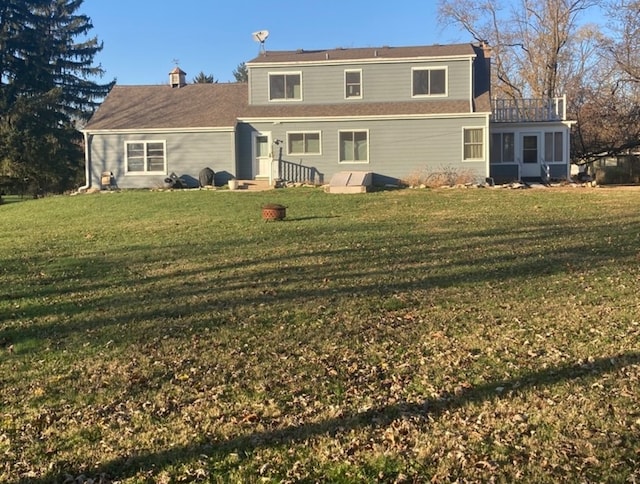 back of house featuring a lawn and a balcony